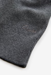 Tmavosivá ponožka s rebrovanou textúrou a hladkým povrchom, ozdobená vyšívaným logom "Clarks" v nenápadnej farbe.