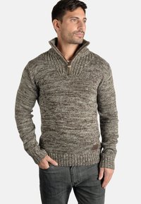Knit sweater in shades of brown and cream with a high collar and zip detail. Ribbed cuffs and hem feature a textured pattern.