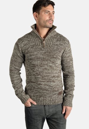 Maglione lavorato a maglia nelle tonalità di marrone e crema con un colletto alto e dettagli con zip. Le maniche riempite e l'orlo presentano un motivo testurizzato.