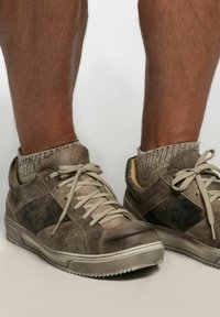 Braune Wildledersneaker mit beigen Akzenten, strukturierten Oberflächen, flachen Schnürsenkeln und Gummi-Sohlen; getragen mit grauen, gestrickten Knöchelsocken.