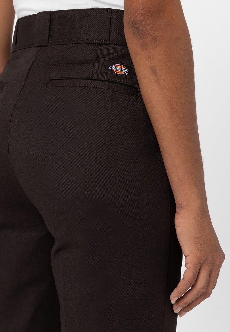 Pantalones negros con un bolsillo trasero de parche con el logo de Dickies. La tela tiene una textura suave y una silueta ajustada.