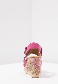 Sandal con tacco a cuneo in suede rosa con cinturino alla caviglia e tacco intrecciato, caratterizzato da ricami floreali in viola e beige.
