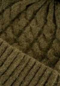 Gorro de lana marrón trenzado con un patrón de diamantes texturizado en el cuerpo principal y detalles de canalé en el borde. Textura suave y aterciopelada.