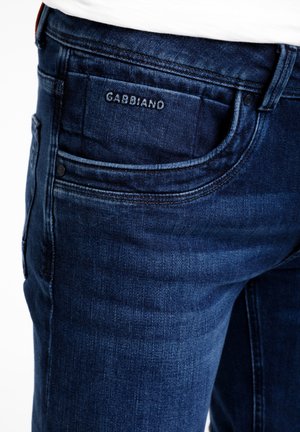 Jeans aus dunkelblauem Denim mit strukturierter Oberfläche. Sie verfügen über eine Gesäßtasche mit geprägtem Logo und Kontrastnähten entlang der Nähte.