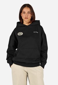 Μαύρη βαμβακερή hoodie με τσέπη καγκουρό, διαθέτει κυκλικό μπατζάκι και το κέντημα "PEGADOR" στην περιοχή του στήθους. Χαλαρή εφαρμογή, ριμπ μανσέτες.