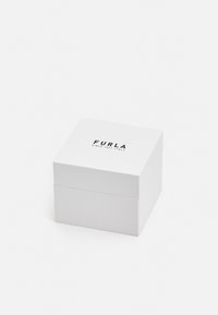 Baltas kvadratinis dėžutė su lygiu paviršiumi, turinti matinį finišą ir juodą tekstą "FURLA" bei "SINCE 1927 ITALY" viršuje.