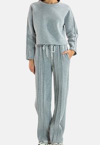 Light gray, long-sleeved sweatshirt with a rounded neckline, paired with matching wide-leg pants featuring vertical stripes and a drawstring waist.