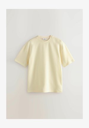 Kollane puuvillane T-särk, millel on ümmargune kaelus, lühikesed varrukad ja lõdva lõige. Omab tekstuurset kangast, et lisada huvitavust.