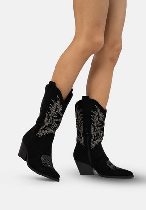 Stivali da cowboy in suede neri con ricami metallici argento, punta affusolata e tacco spesso. Presentano una chiusura con zip e cuciture decorative.