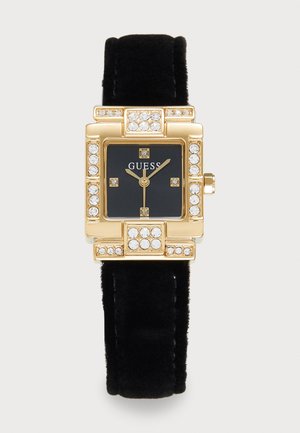 Orologio Guess con quadrante quadrato dorato, cinturino in velluto nero, quadrante nero, indicatori di ore in cristallo e dettagli in cristallo sulla lunetta.