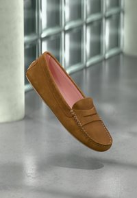 Smeđi suknjeni loafers s ukrasnim šavom i glatkim roza unutrašnjim dijelom, zaobljenog vrha i niskog profila.