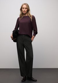 Blusa de manga larga color burdeos con escote redondo, combinada con pantalones de pierna ancha gris oscuro y botas negras. Diseño minimalista, textura suave.