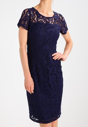 Marineblauwe kanten jurk met een aansluitende pasvorm, korte mouwen, bloemenpatroon en een zoom tot op de knie. Voorzien van een ronde halslijn.