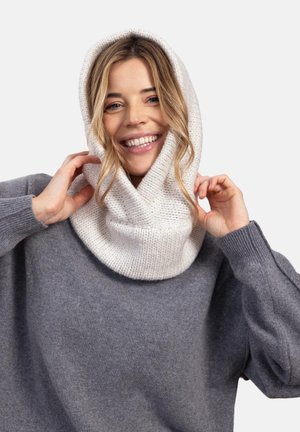 Kremowa dzianinowa kominiarka o teksturowanym wzorze, noszona luźno wokół szyi. Towarzyszy jej szary, oversize'owy sweter o szerokich rękawach.