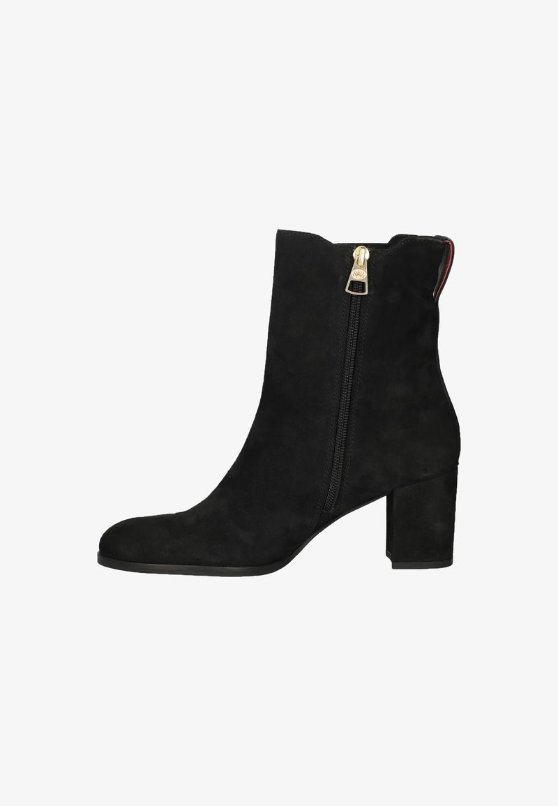 Botín de ante negro hasta el tobillo con tacón cuadrado, presenta una cremallera lateral y detalles en dorado. Textura suave con una silueta simplificada.