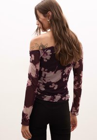 Dlhý rukáv, off-the-shoulder top v tmavofialovej farbe s jemnými kvetinovými vzormi. Slim fit, zhrubené strany, mäkká tkanina a textúrované akcenty.