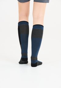 Knälånga strumpor med ett randigt mönster i nyanser av blått, grått och svart. Tillverkade av ett texturerat stickat material.