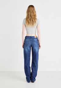 Ανοιχτό γκρι κοντομάνικο μπλουζάκι σε συνδυασμό με φαρδιά, μεσαίου μπλε τζιν παντελόνια που διαθέτουν δύο πίσω τσέπες και καφέ δερμάτινη ετικέτα στη μέση.