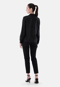 Black long-sleeve blouse with a collar, paired with slim black pants and black high-heel sandals, showcasing a smooth texture and fitted design.