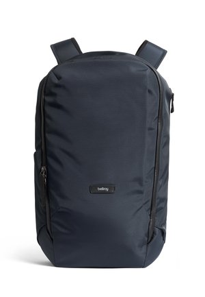 Zaino Bellroy blu navy con spallacci imbottiti, scomparto frontale con cerniera e design minimalista su sfondo bianco.