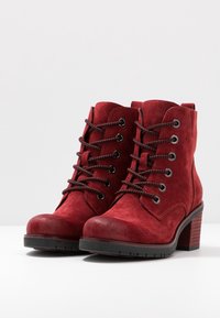 Rote Wildleder-Ankle Boots mit Schnürdesign, abgerundeter Zehenform und robustem Absatz. Verfügt über schwarze Schnürsenkel und kontrastierende Nahtdetails.