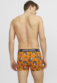 Boxers naranjas con un patrón de calaveras y flores, con una cinturilla negra que lleva el logo "JACK & JONES" y un diseño ajustado.