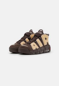 Bruna sneakers med beige accenter, med stort "AIR"-märke, vadderad krage och gummisula för grepp. Tillverkade av mocka och mesh-material.