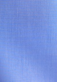 Tessuto strutturato in una tonalità di azzurro chiaro, con un motivo a griglia di piccoli puntini equidistanti che creano un aspetto uniforme.