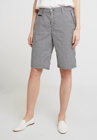 Bermuda shorts a righe in bianco e nero, con chiusura a bottone, passanti per cintura e tasche laterali. Tessuto leggero con una superficie liscia.