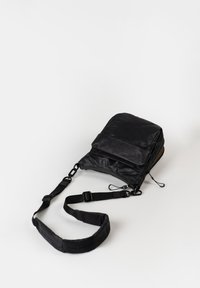 Schwarze Nylon-Schultertasche mit verstellbarem Riemen, Reißverschluss-Hauptfach und umklappbarem Deckel. Glatte Textur, minimalistisches Design.