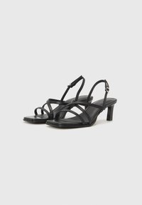 Black heeled sandals with a slim design, featuring multiple crossed straps and a buckled ankle strap. Made of smooth leather.