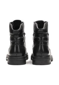 Botas de tobillo de cuero negro con un acabado suave, acentos texturizados, punteras redondeadas y una suela de goma duradera. Presenta detalles de costura mínimos.