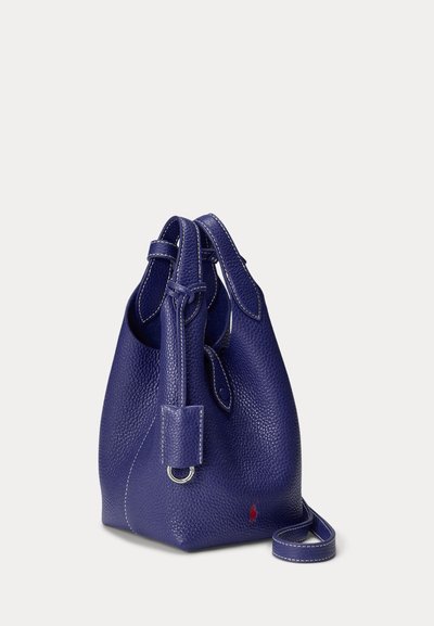 Dark blue textured leather bucket bag with adjustable strap, silver ring detail, and small red logo on the lower front side.