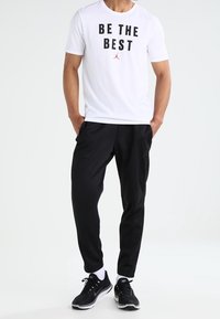 White T-shirt with "BE THE BEST" in black text and a red logo, paired with black athletic pants and black sneakers. Simple, sporty design.