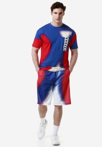 Camiseta de manga corta azul y roja con bolsillo, combinada con pantalones cortos a juego en azul y rojo. Hecha de un tejido ligero con una textura suave.