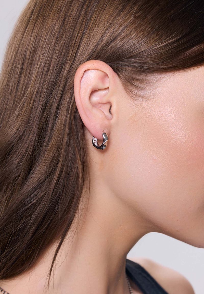 Srebrna kolczyk kolowy z skręconym wzorem, łączący błyszczące i matowe wykończenia, prezentujący gładką powierzchnię i minimalistyczny styl.