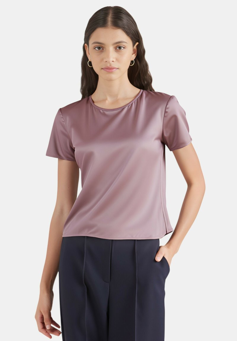 Top in raso a maniche corte di un morbido color malva con scollo rotondo, dalla vestibilità rilassata e texture liscia, abbinato a pantaloni scuri.