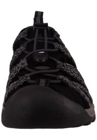 Chaussure noire en matériau texturé, dotée de lacets élastiques et d'une semelle en caoutchouc. Design épuré avec un bout arrondi et des accents moulés.