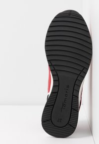 Baskets rouges et blanches avec une semelle extérieure en caoutchouc noir. Présente un motif de prise texturé et un branding sur la semelle. Design à embout rond.