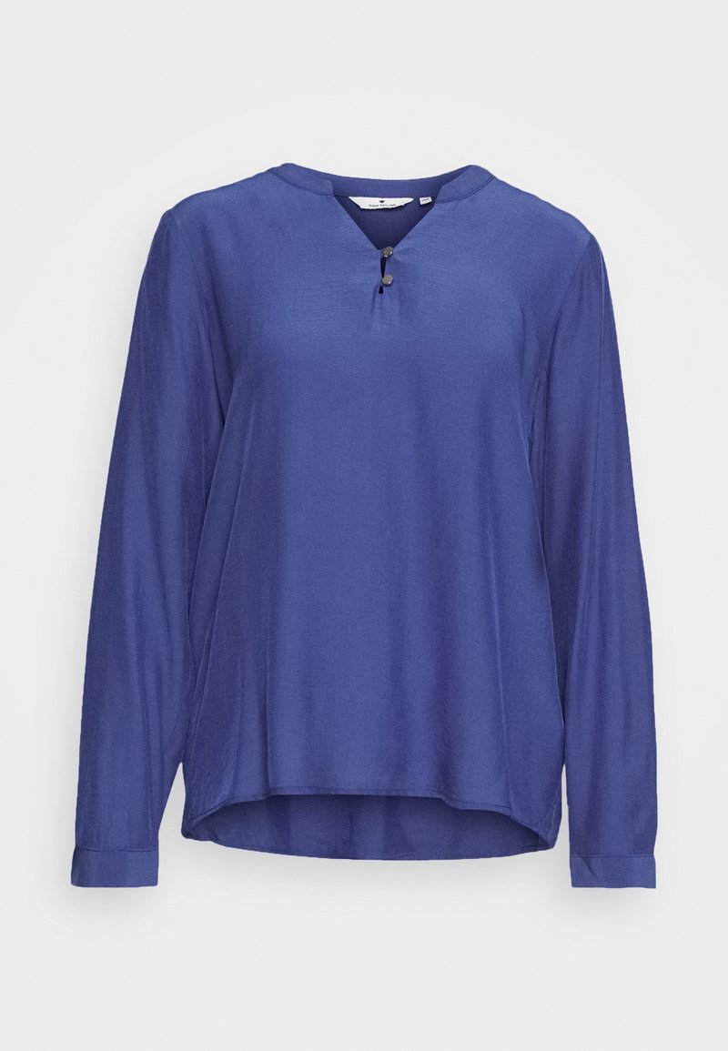 Top bleu à manches longues en tissu lisse, avec un col en V orné d'un détail bouton et un ourlet légèrement incurvé.