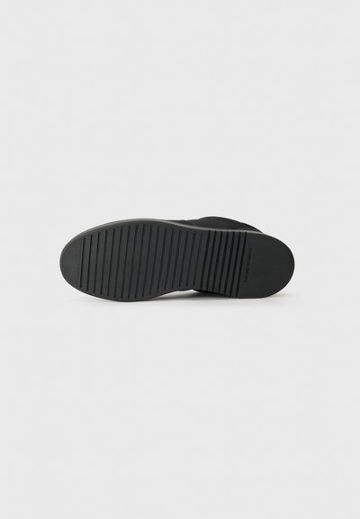 Black footwear sole with ridged texture, circular heel, and flat design. Made from rubber, featuring no distinguishable patterns or accents.