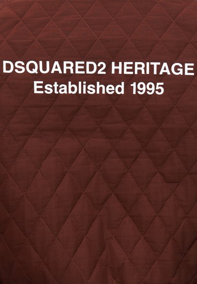 Tissu matelassé marron avec le texte blanc "DSQUARED2 HERITAGE Established 1995" centré sur la surface.