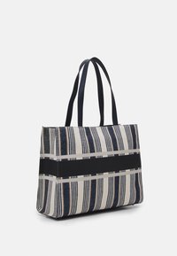 Tygväska i vävt tyg med marinblå och cremefärgade vertikala ränder. Har två handtag i svart läder och en svart accentrand.