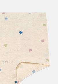 Bawełniana bielizna w odcieniu beżowym o miękkiej teksturze, z małymi, kolorowymi wzorami serc w odcieniach niebieskiego, zielonego i różowego.