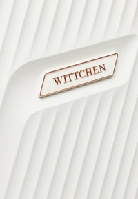 Weißer, strukturiert Reisekoffer mit vertikalen Rillen und einer rechteckigen Metallmarke mit der Aufschrift "WITTCHEN" in Roségold.