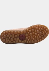 Shoe sole with a textured rubber surface featuring rounded bumps in varying sizes, colored in light brown with a red circular logo.