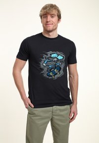 Camiseta de algodón negra con un gráfico colorido de un patinador en acción. El diseño incluye elementos en azul y gris con detalles.