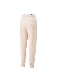 Pantalones de chándal rosa claro con un corte holgado, puños acanalados y cinturilla elástica. Detallados con dos bolsillos traseros. Textura suave.
