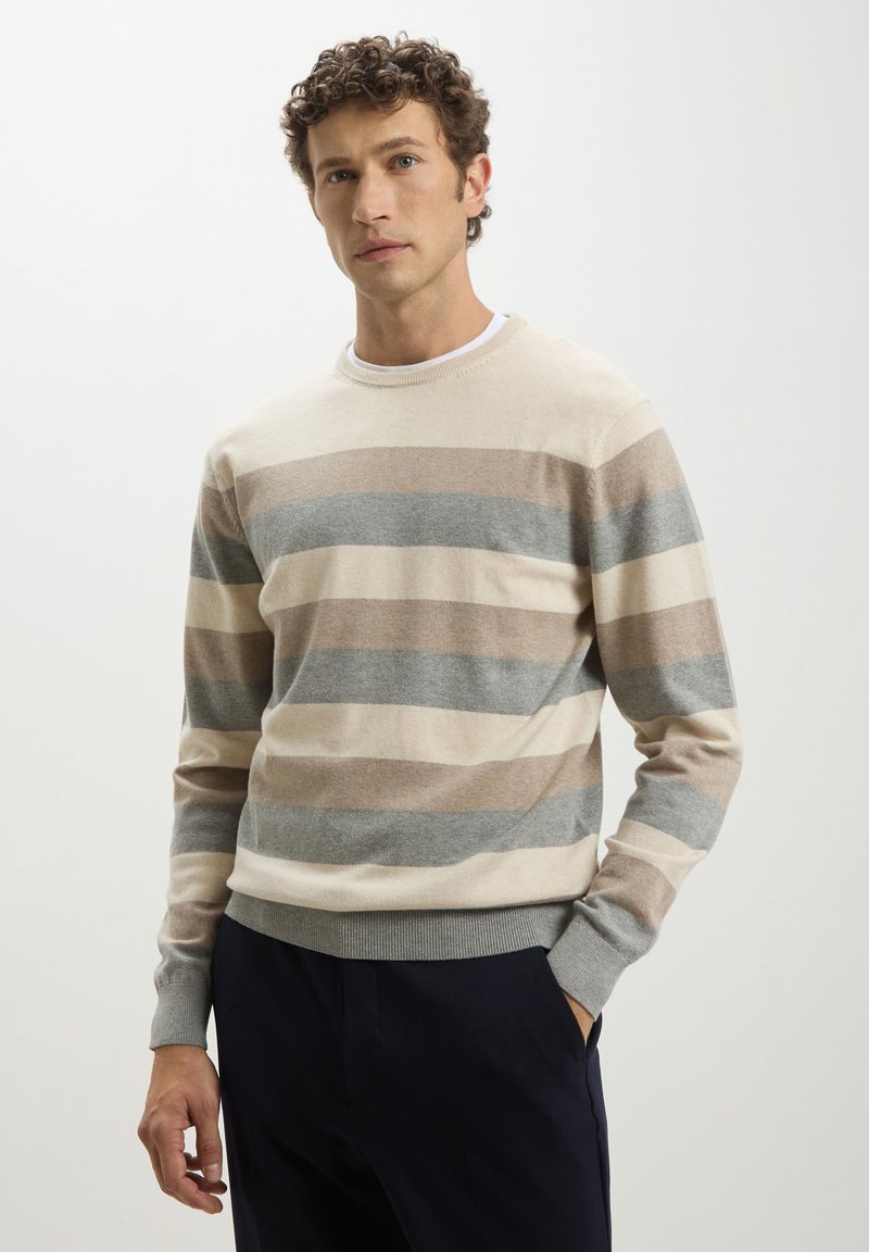 Maglione a righe beige e grigio realizzato in tessuto morbido, con collo a giro e polsini a coste. Le righe variano in larghezza e colore.