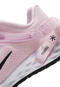 La chaussure de sport rose présente une tige texturée, un logo swoosh noir, une large sangle élastique et une semelle blanche rembourrée avec une semelle extérieure noire.